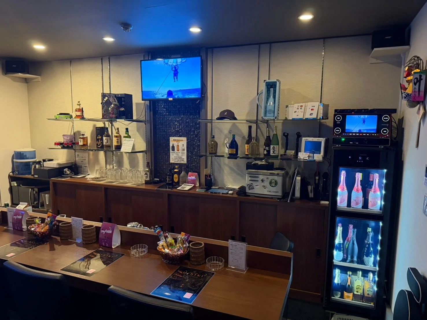 流川の夜景を背に木のカウンターとボトル棚が伸びる占いバー店内を正面から捉えた写真